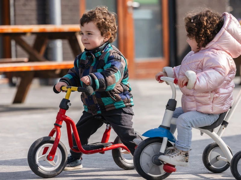 kinderen fietsen op het plein van bso